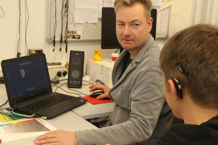Martin Schiffkowski, Mitentwickler des Oldenburger Cochlea Implantat Trainers vom AWO Sprachheilzentrum, erklärt einem Träger eines Cochlea Implantats den häuslichen Gebrauch der Software. <span>Foto: Piet Meyer/Jade HS</span>