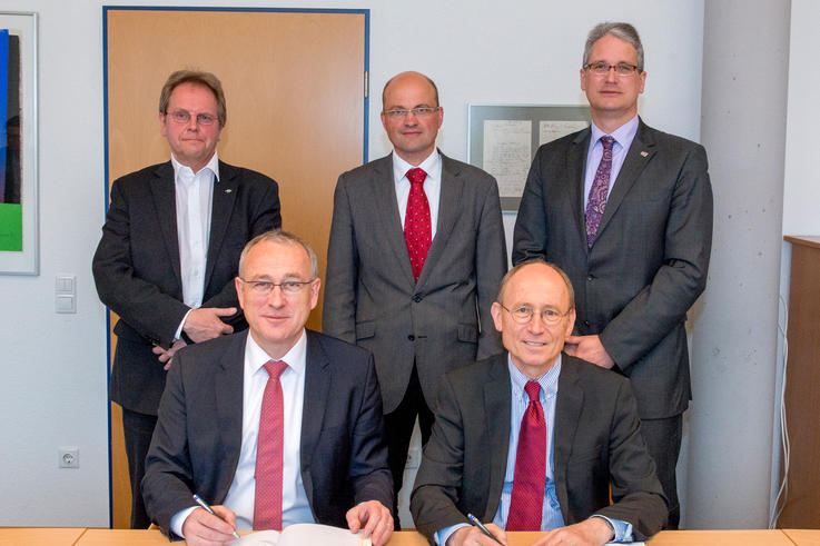 Der Präsident der Universität, Prof. Dr. Dr. Hans Michael Piper (vorne rechts) und der Präsident der Jade Hochschule, Prof. Dr.-Ing. Manfred Weisensee, unterzeichnen die Kooperationsvereinbarung. Gemeinsam mit dem Vizepräsidenten für Verwaltung und Finanzen der Universität, Jörg Stahlmann (hinten rechts), und dem Vizepräsidenten der Jade Hochschule für Personal, Verwaltung und Liegenschaften, Markus Wortmann (hinten links), setzen sie auch weiterhin auf einen reibungslosen Gebäudebetrieb an beiden Hochschulen unter Leitung von Dezernent Meik Möllers (Mitte). <span>Foto: Universität Oldenburg / Daniel Schmidt</span>